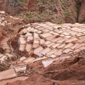 Terrasses des salineras de Maras. Une personne remplie des sacs de sel. Exploitation de sel. L'eau d'une source riche en sel est guidée dans les terrasses, l'eau s'évapore, reste le sel. Balcons. Pérou.