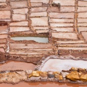 Terrasses des salineras de Maras. Une personne remplie des sacs de sel. Exploitation de sel. L'eau d'une source riche en sel est guidée dans les terrasses, l'eau s'évapore, reste le sel. Balcons. Pérou.