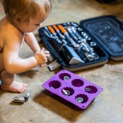 Bebe petite fille en train de jouer avec des outils et un moule a gateau. Cuisine mecanique. Outils. Dans l'atelier de son papa.