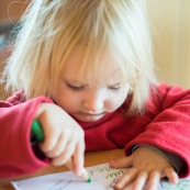 Portrait de petite fille en train de dessiner et d'apprendre a ecrire. Crayon de couleur vert.