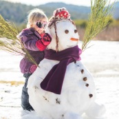 Petite fille et bonhomme de neige. En montagne dans les Cévennes (l'Esperou, proche du Mont Aigoual).