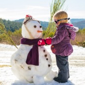 Petite fille et bonhomme de neige. En montagne dans les Cévennes (l'Esperou, proche du Mont Aigoual).