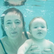 Portrait de bebe sous l'eau. Sa maman a proximite. Bebe avec des lunettes sous l'eau dans une piscine. En train d'apprendre a nager.